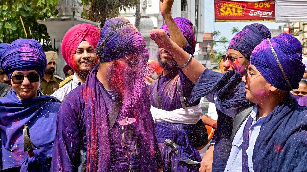 Sikh warriors play with coloured powder during the festival