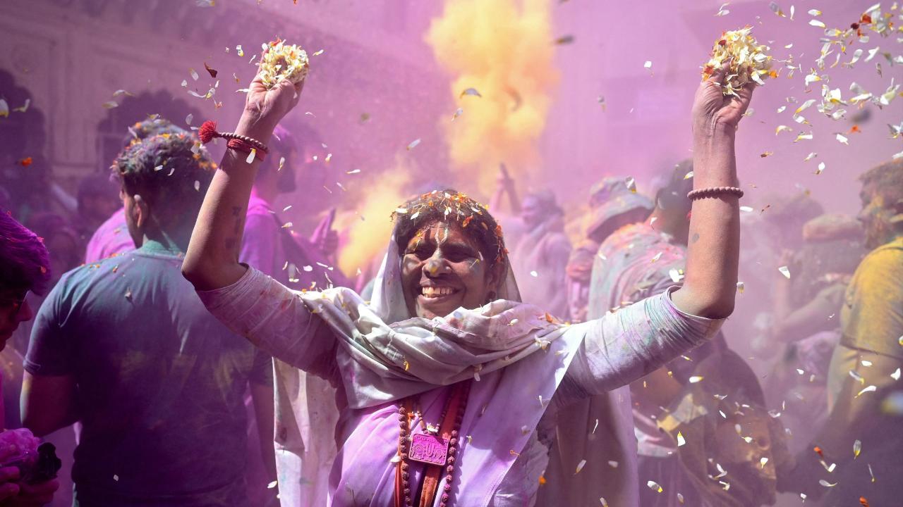 A widow is seen throwing flower petals, participating in the festivities as the temple is covered with  vibrant colours 