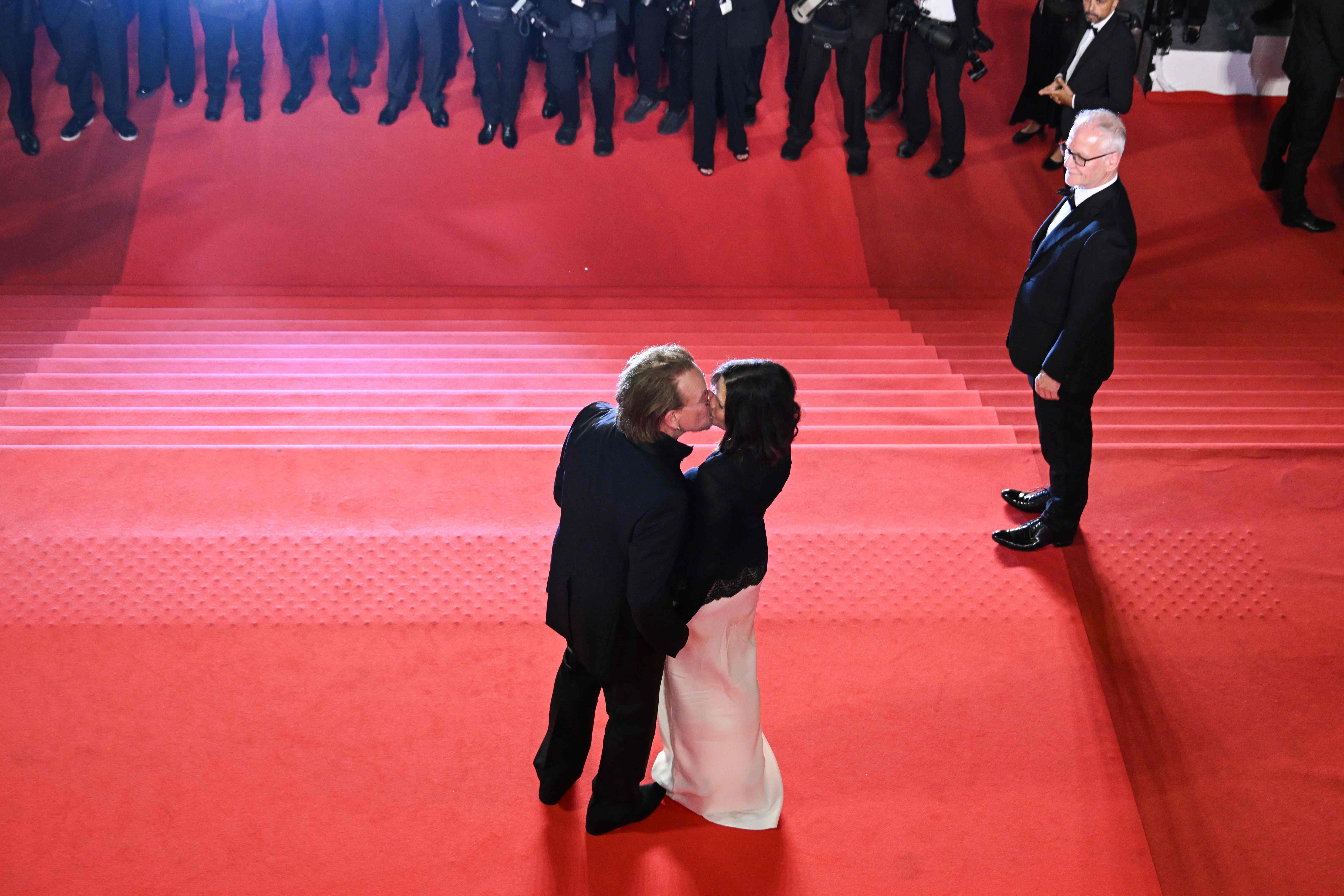 Irish singer-songwriter and executive producer Bono kissed his wife, Irish activist and businesswoman Ali Hewson, as they left after the screening of Bono: Stories of Surrender at the 78th Cannes Film Festival, with festival director Thierry Frémaux seen alongside them