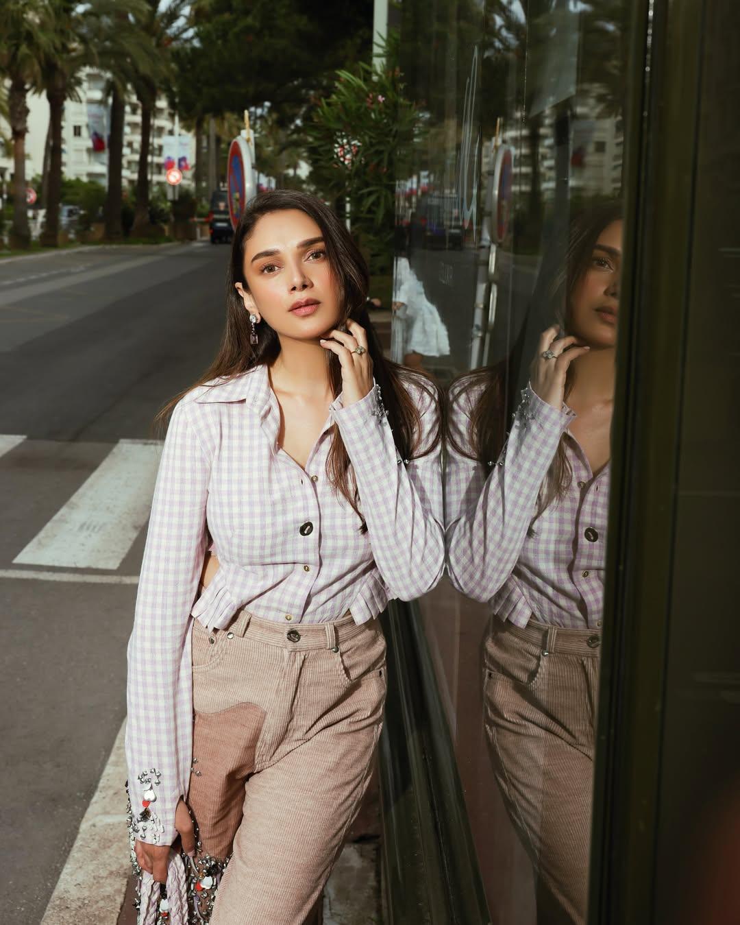 Her relaxed ensemble from GRAINE featured a pink-and-white checkered shirt with cool side cut-outs, pleated detailing, and delicate embroidery, a standout piece for off-duty fashion inspiration