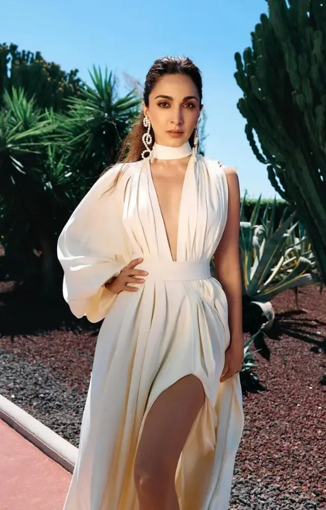 Kiara Advani made her much-anticipated Cannes debut in 2024. Ahead of her red carpet walk, she teased her look in a video. The actor wore an ivory outfit with a plunging neckline and thigh-high slit, accessorised with statement earrings and matching heels