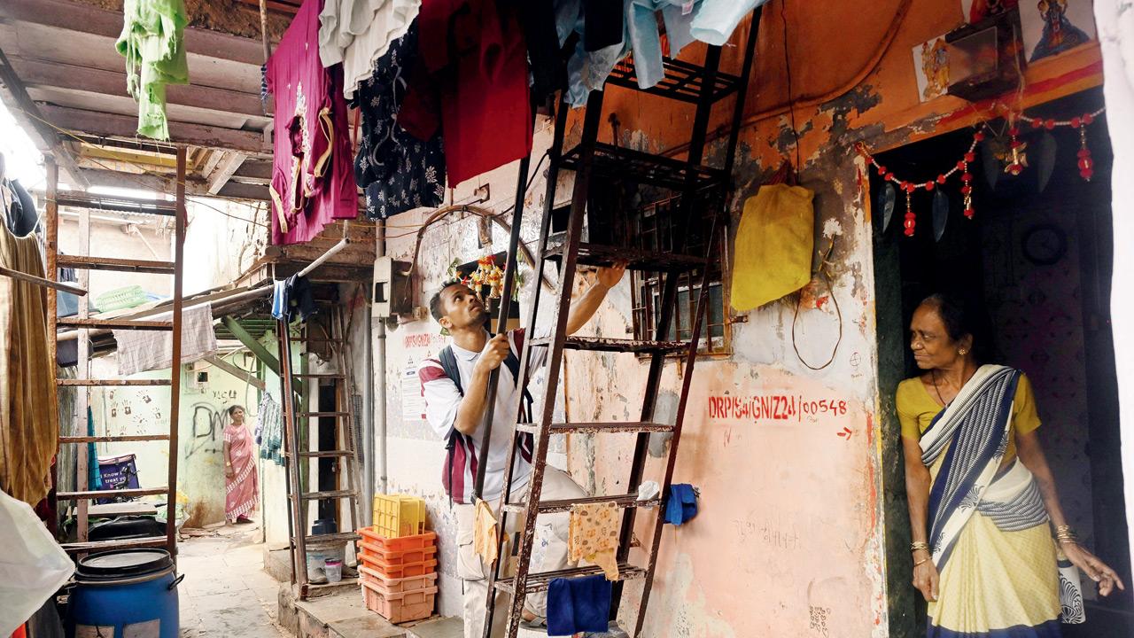 Methari climbs up a ladder to his room in Mukund Nagar, Dharavi