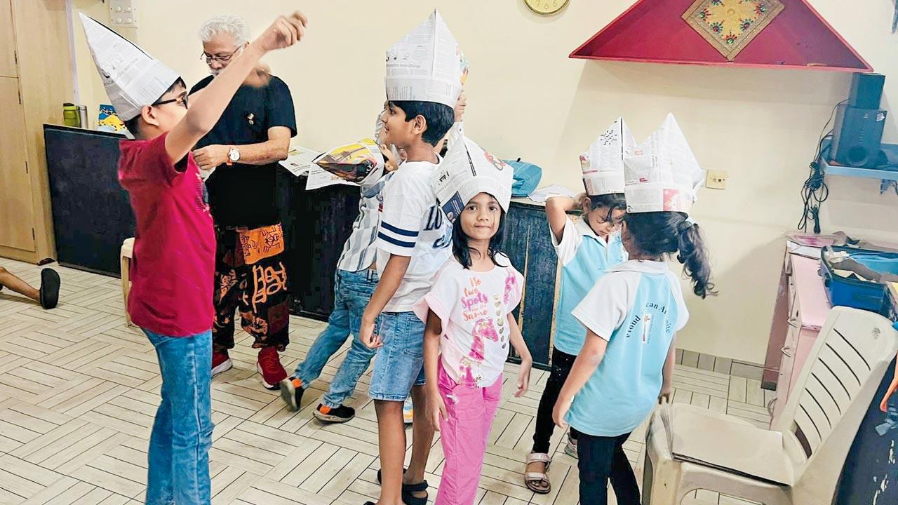 Children wear caps made using waste paper at a previous workshop