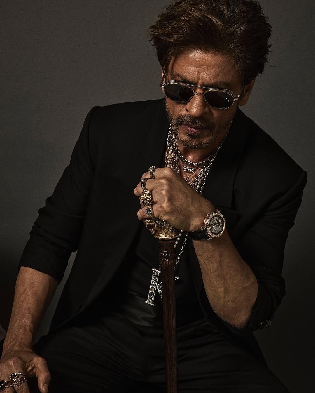 Suiting the theme of the evening, Shah Rukh Khan made a bold appearance by ditching the shirt for a vest layered with a long blazer. While the multiple necklaces surely enhanced his appearance, it was that big K (King) around his neck that brought the right amount of drama to his look. With his tousled hair, black sunglasses, a cane in hand, and a statement brooch on his lapel, Shah Rukh ate and left no crumbs