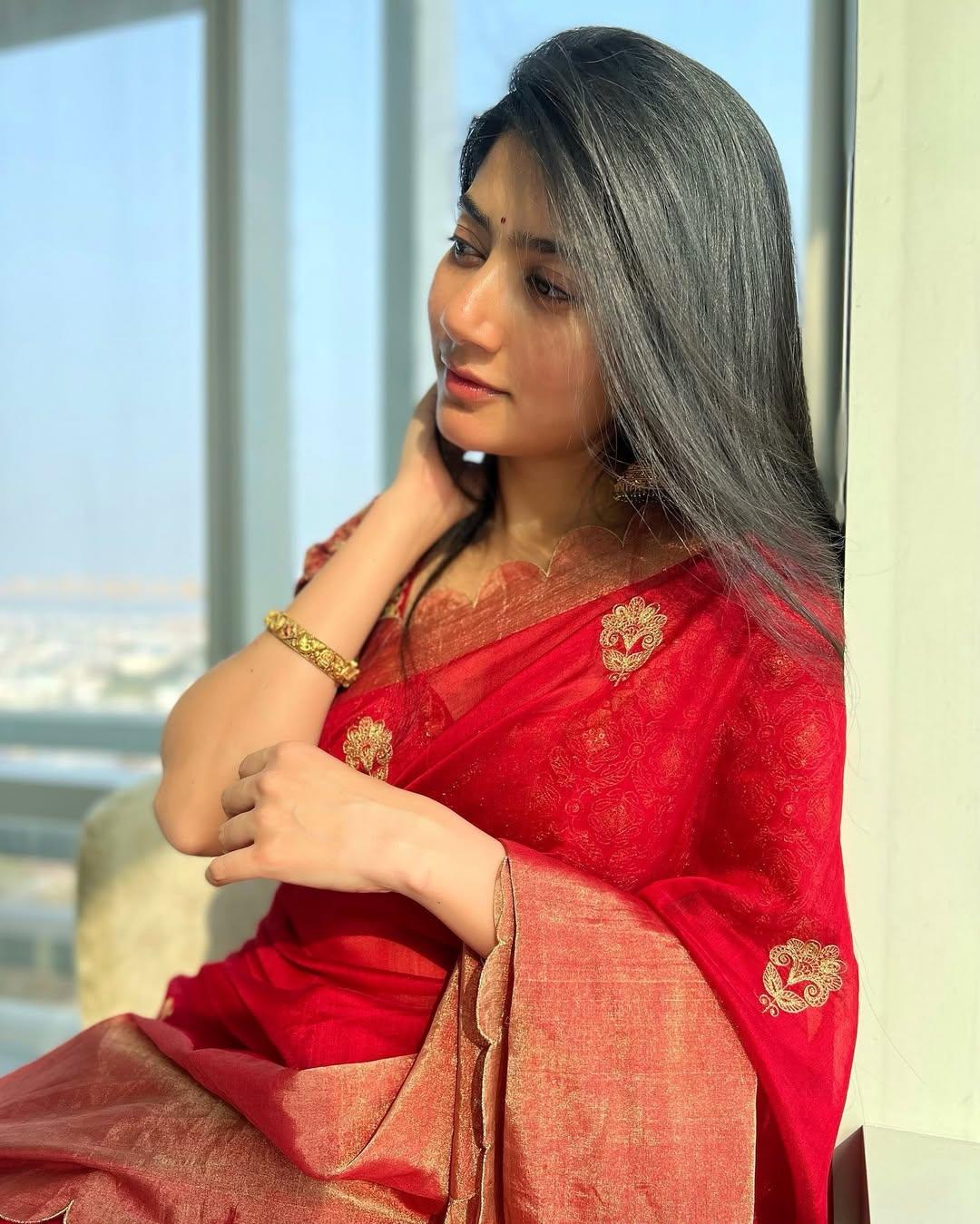 Have a wedding to attend? Then what is better than a red saree featuring golden motifs and a stylish border, paired with a matching blouse and a simple kada?
