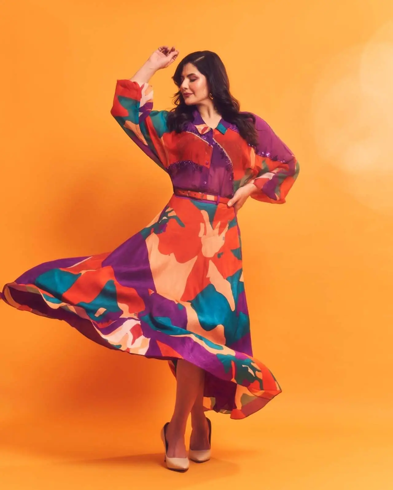 In this appearance, Zareen Khan wore a beautiful multicoloured gown featuring long sleeves and a collared neckline, pairing it with simple footwear—perfect for an everyday office appearance