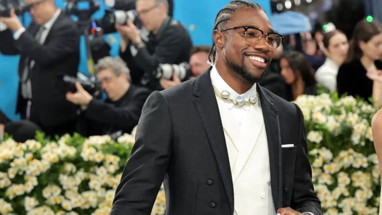 Olympic sprinter Noah Lyles wore a fashion-forward black suit with tailored shorts, high socks, and a cane, blending contemporary edge with classic menswear.