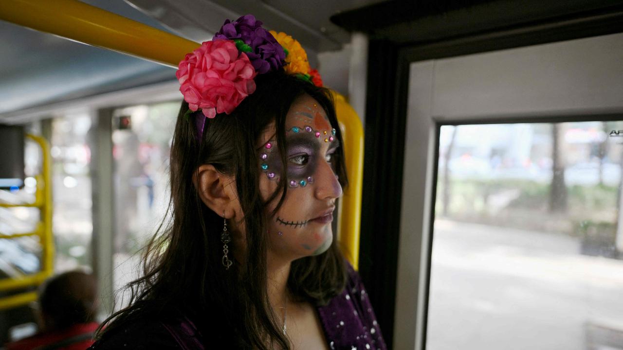 A woman with skull makeup travels on public transport ahead of the Day of the Dead celebration on Reforma Avenue in Mexico City on October 31