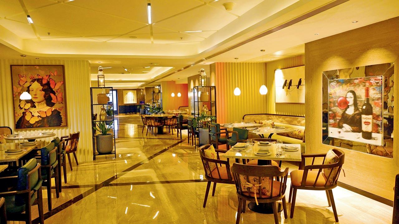 The decor blends contemporary design with rooted charm — AI-reimagined Warli art, vintage film posters, a cheeky Mona Lisa, and antique tiffins set against clean cement lines.