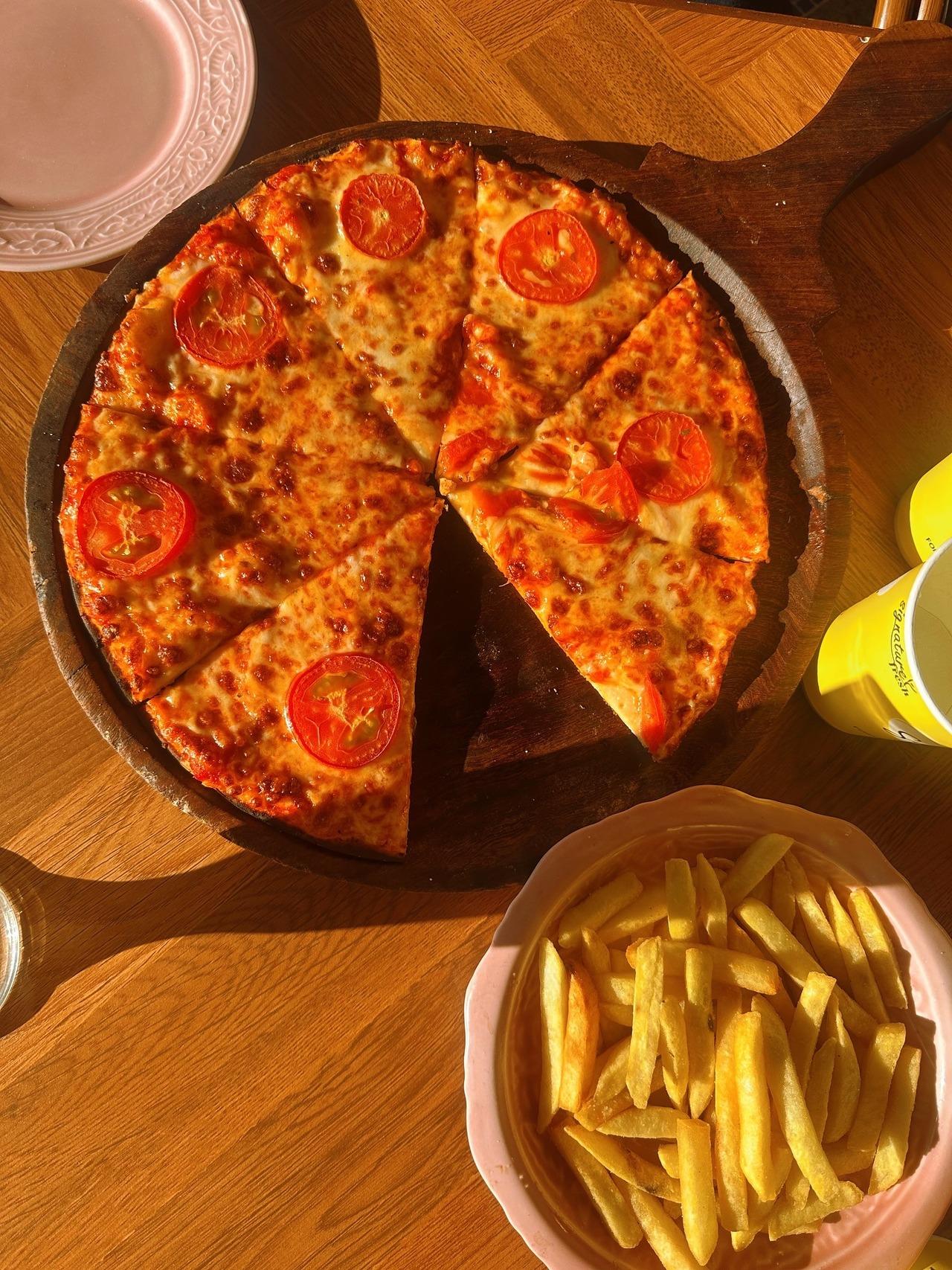 <p>Vacations are incomplete without scrumptious meals. Sheetal shared an aesthetic picture of a delicious pizza placed on a table with fried as the sunrays peaked in.</p>