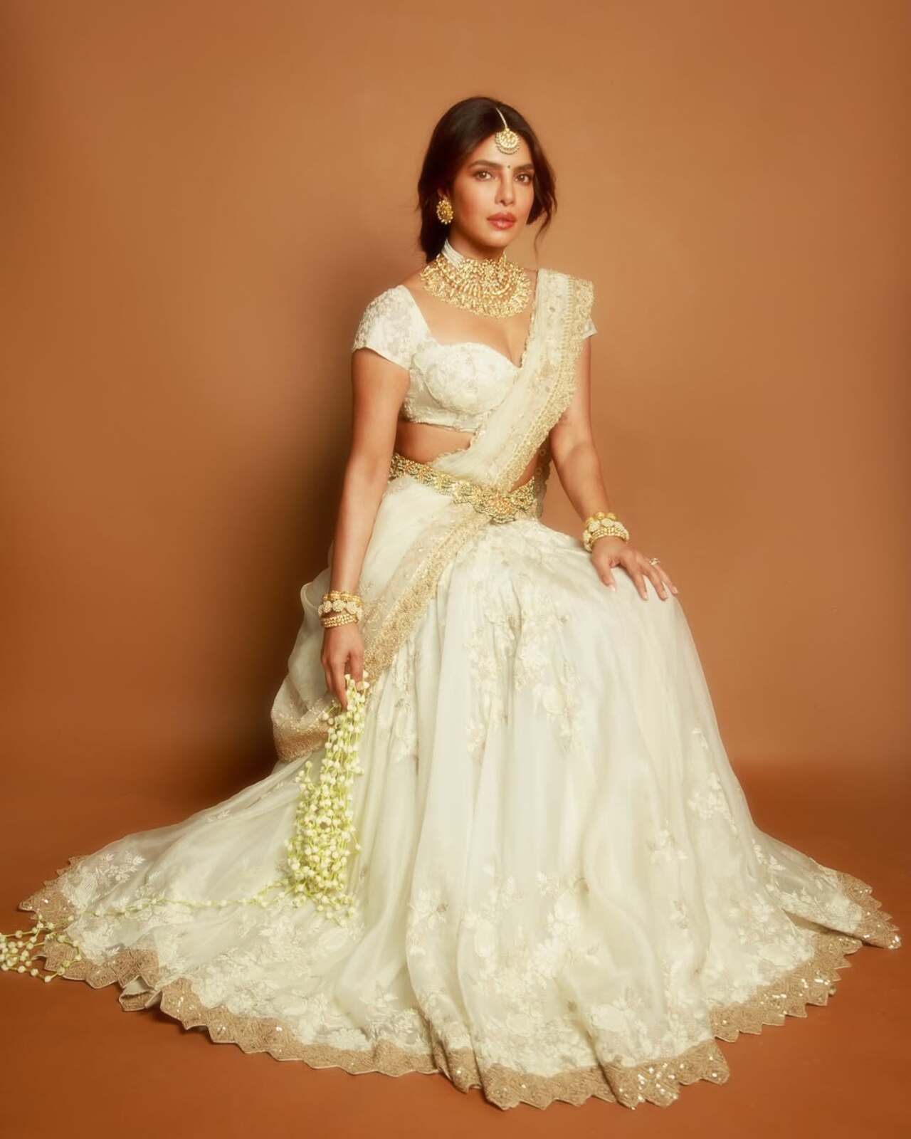 Both wrists are stacked with broad gold bangles, complemented by an elegant ring that completes the accessories.