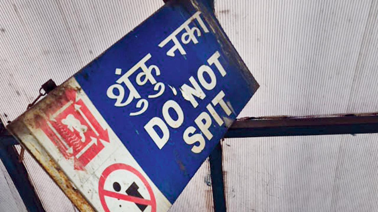 An anti-spitting signboard on the Virar skywalk lies barely hangs on