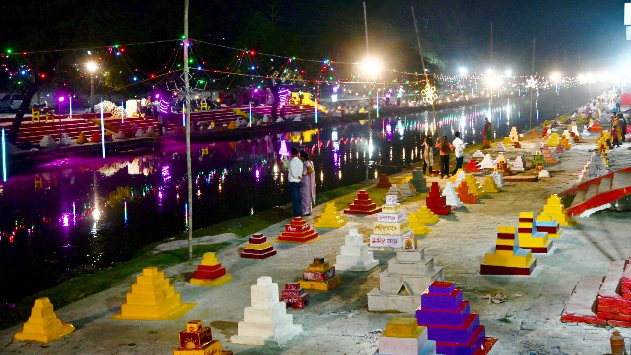 KanpurPeople standing at a ghat decorated with colours and lights.