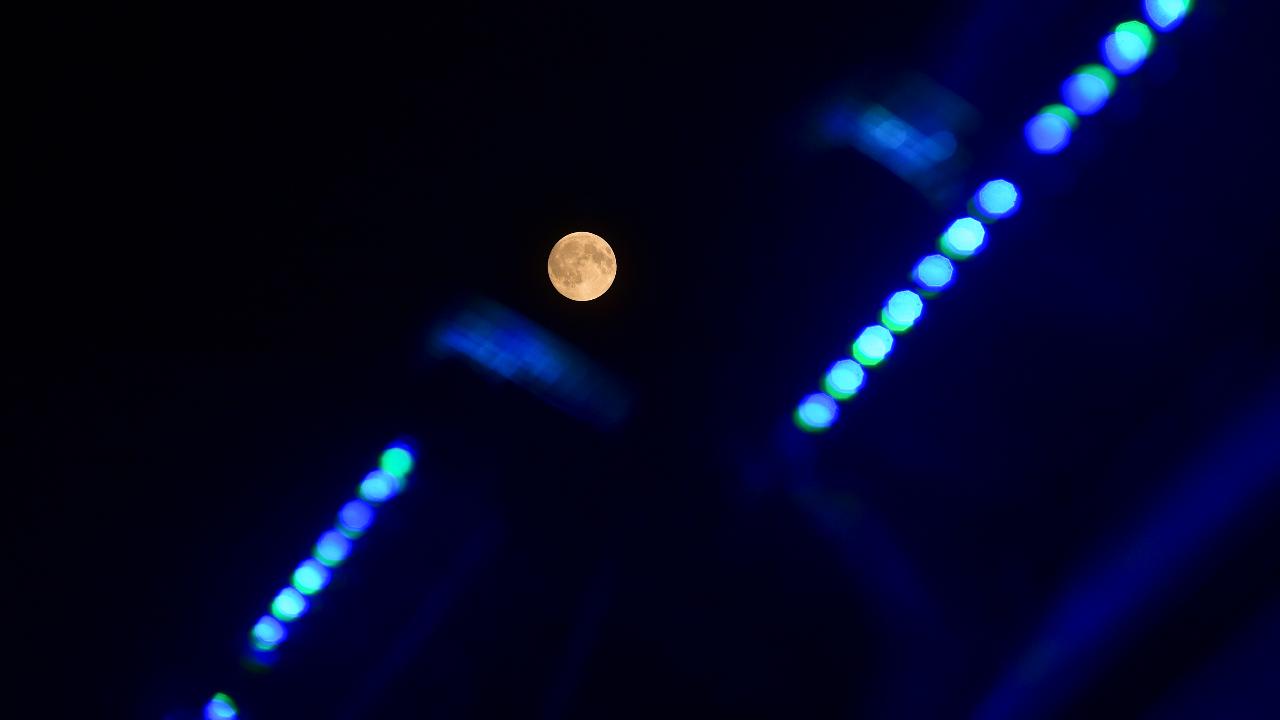 Amid the blues, people in Uttar Pradesh spotted the Supermoon on 'Sharad Purnima' from behind an illuminated building, in Prayagraj