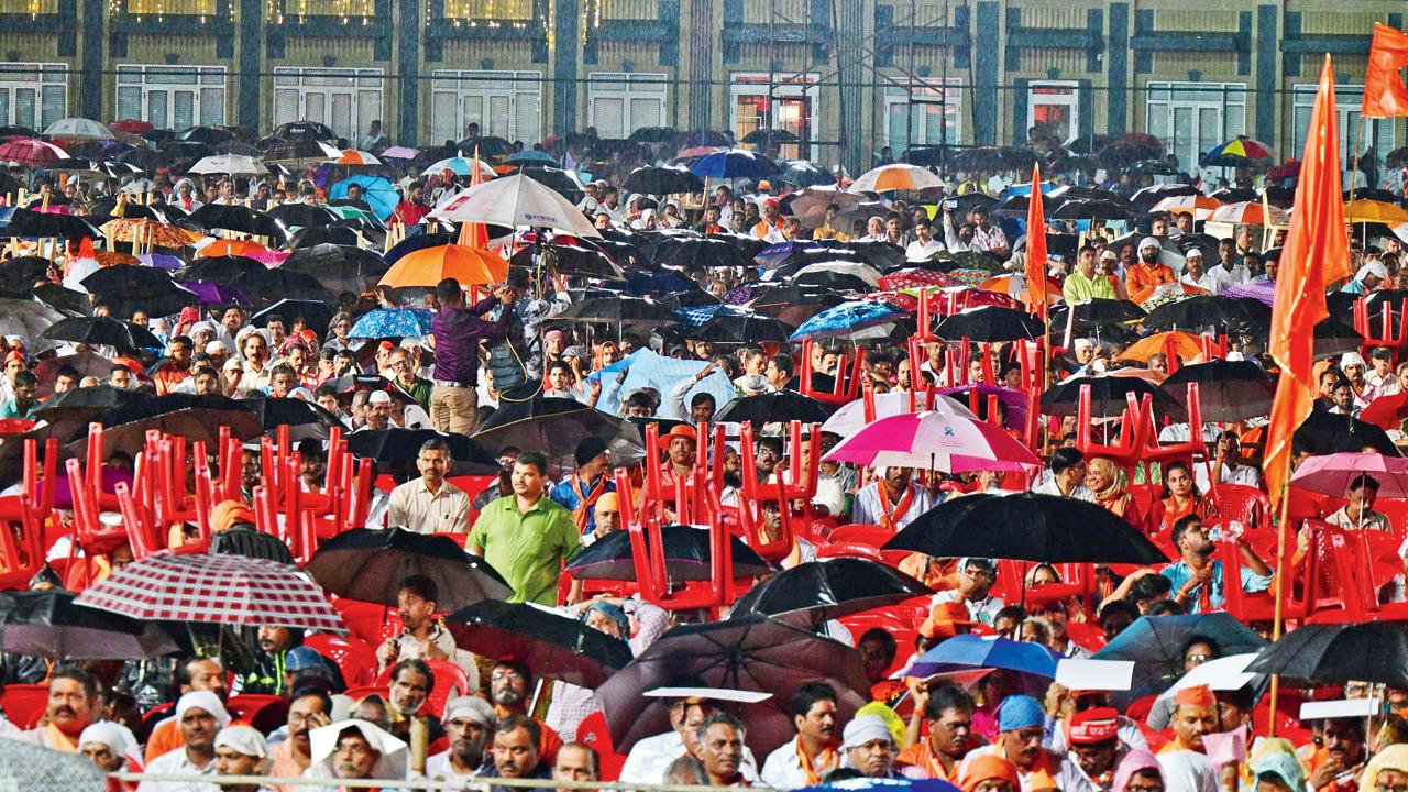 Supporters use chairs and umbrellas to shield themselves from rain as they listen to Uddhav’s speech at Shivaji Park