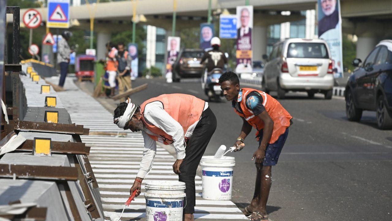 Workers paint a road ahead of Day 2 of the British PM's visit to Mumbai
