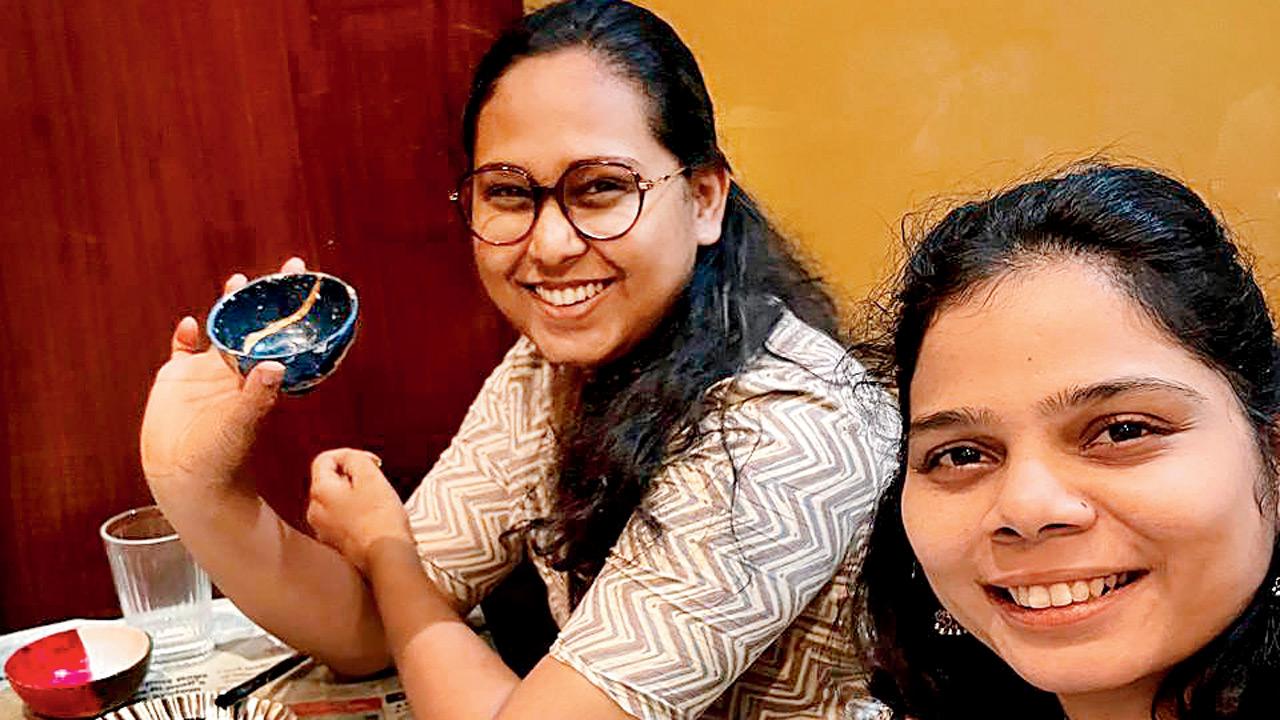Two women show off their repaired ceramic objects