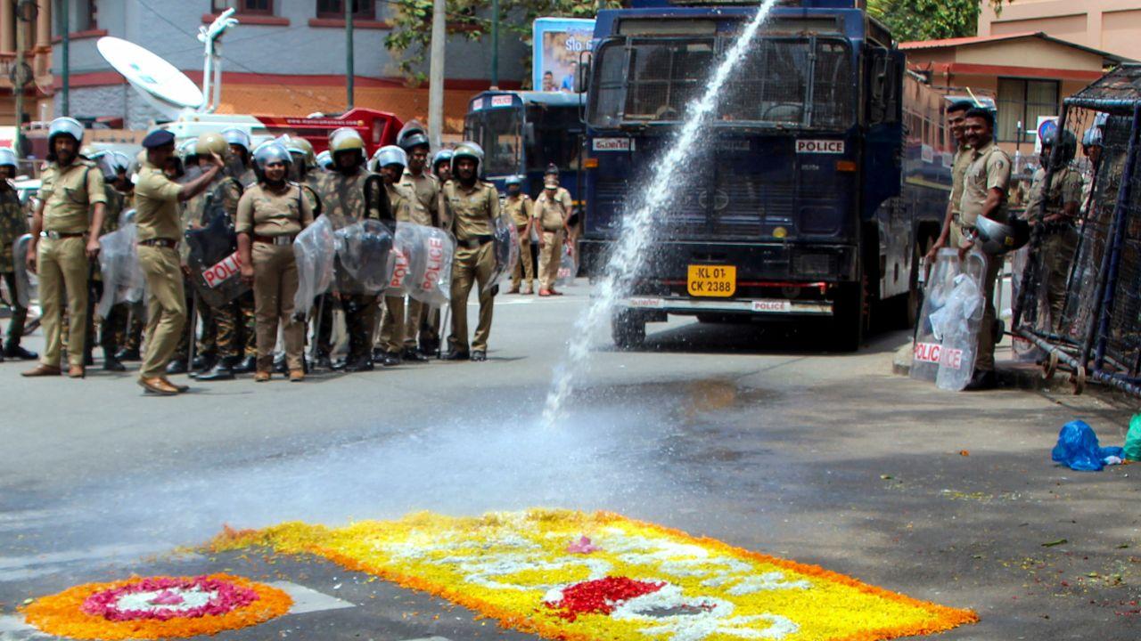  Police personnel use water cannon to remove a ‘pookalam’ made by BJYM