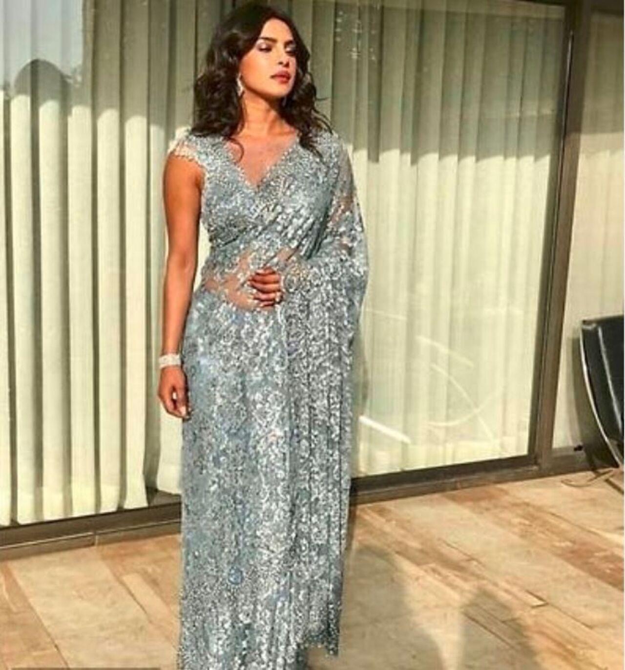 Priyanka Chopra's lace grey saree is sultry and chic. She pairs it with silver jewellery to complete the look.