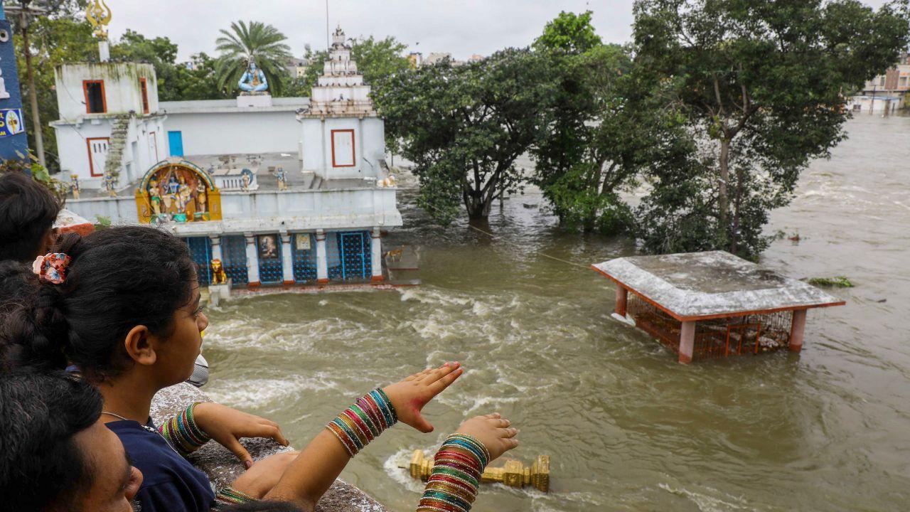 People look at a partially submerged temple at a low-lying area near swollen Musi river following heavy rains, in Hyderabad