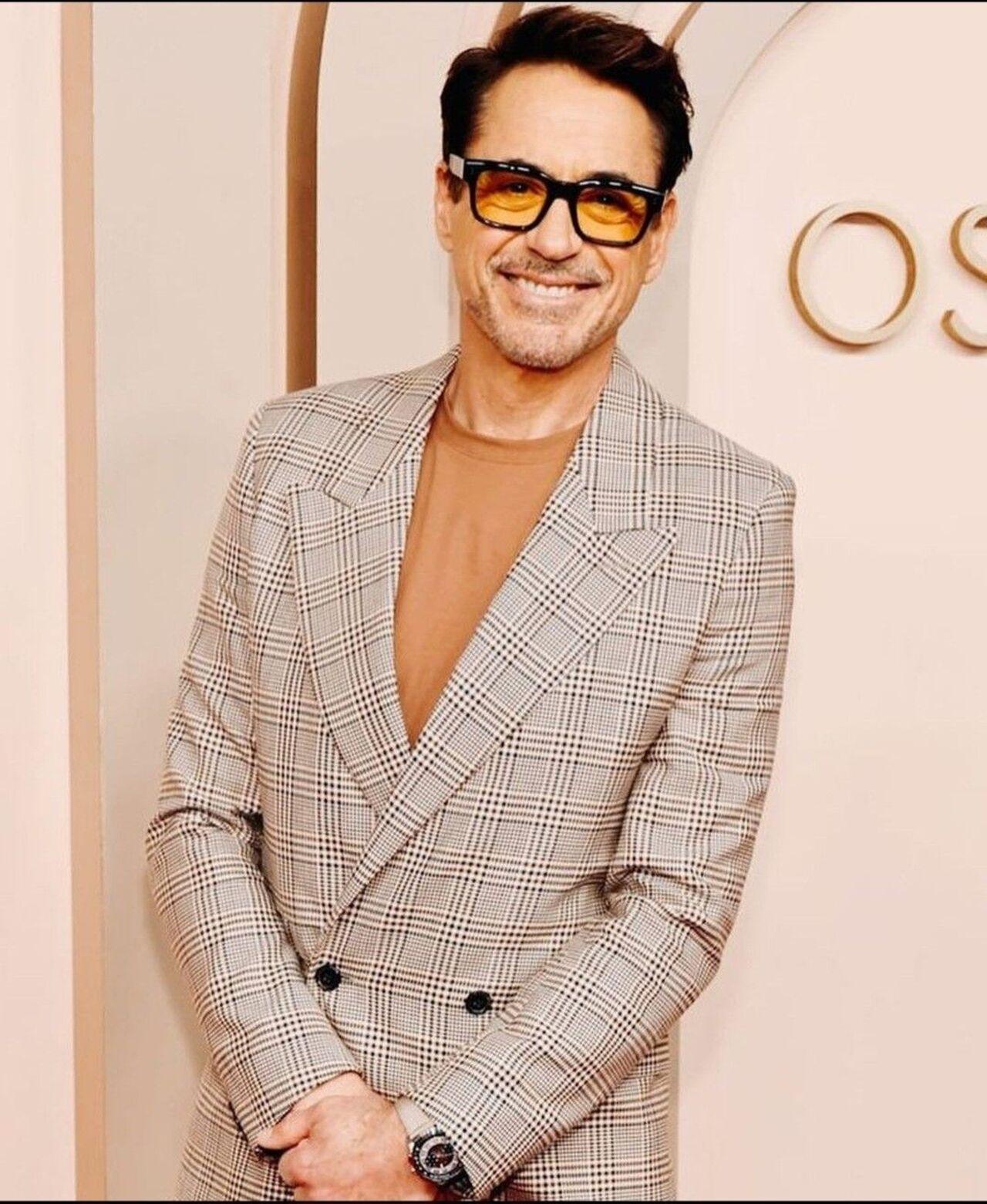 Robert stuns in this woollen brown plaid double-breasted blazer, paired with a plain, solid-colored, light brown t-shirt or thin sweater, making for a casual yet stylish look.