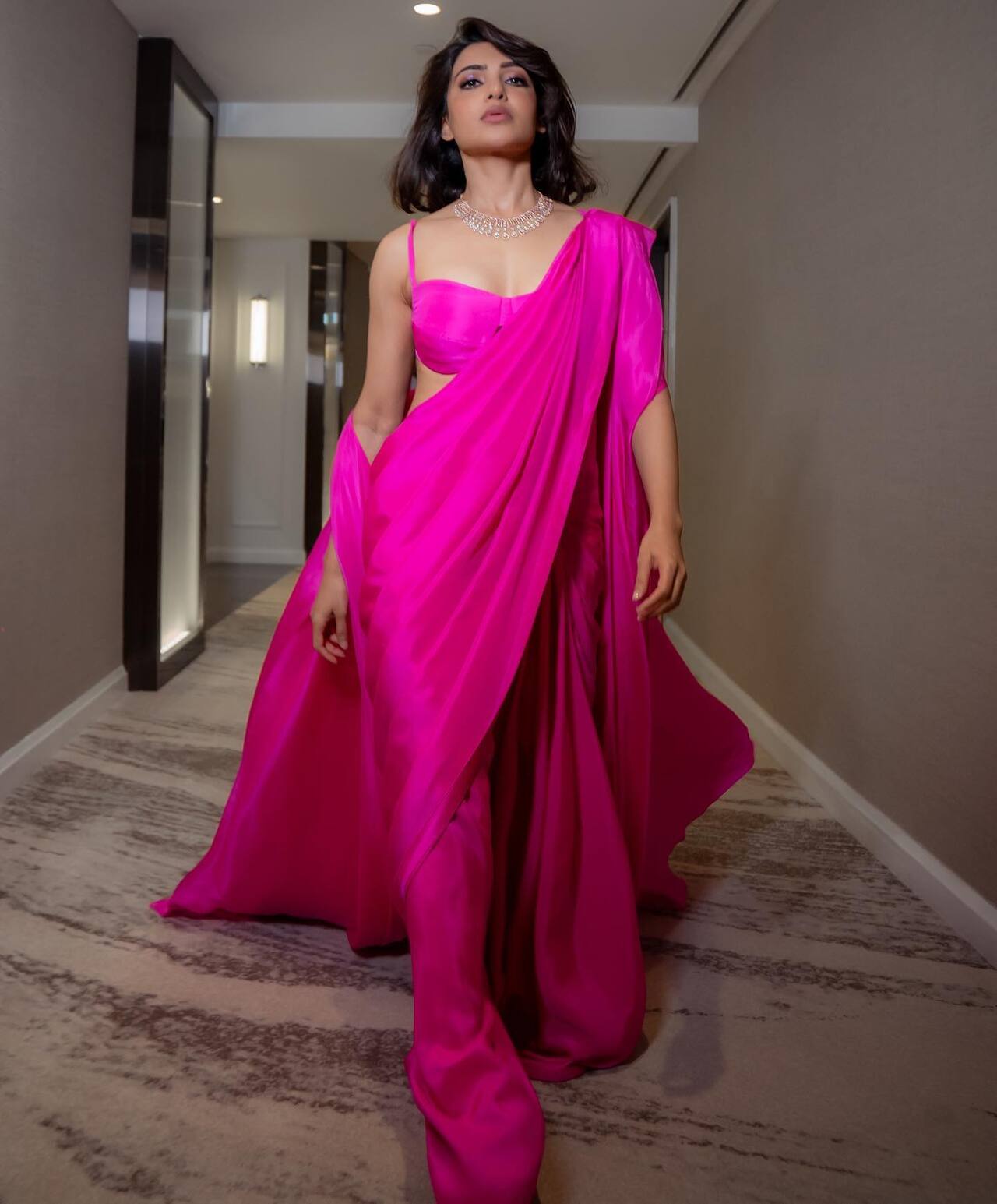 Samantha oozes out glam barbie vibes in this fuschia pink saree paired with strapless blouse. She teamed up look with floor-sweeping cape.