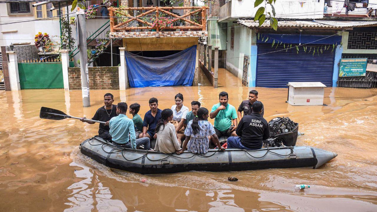 People use an inflatable boat to cross a waterlogged street following heavy rain, in Guwahati.