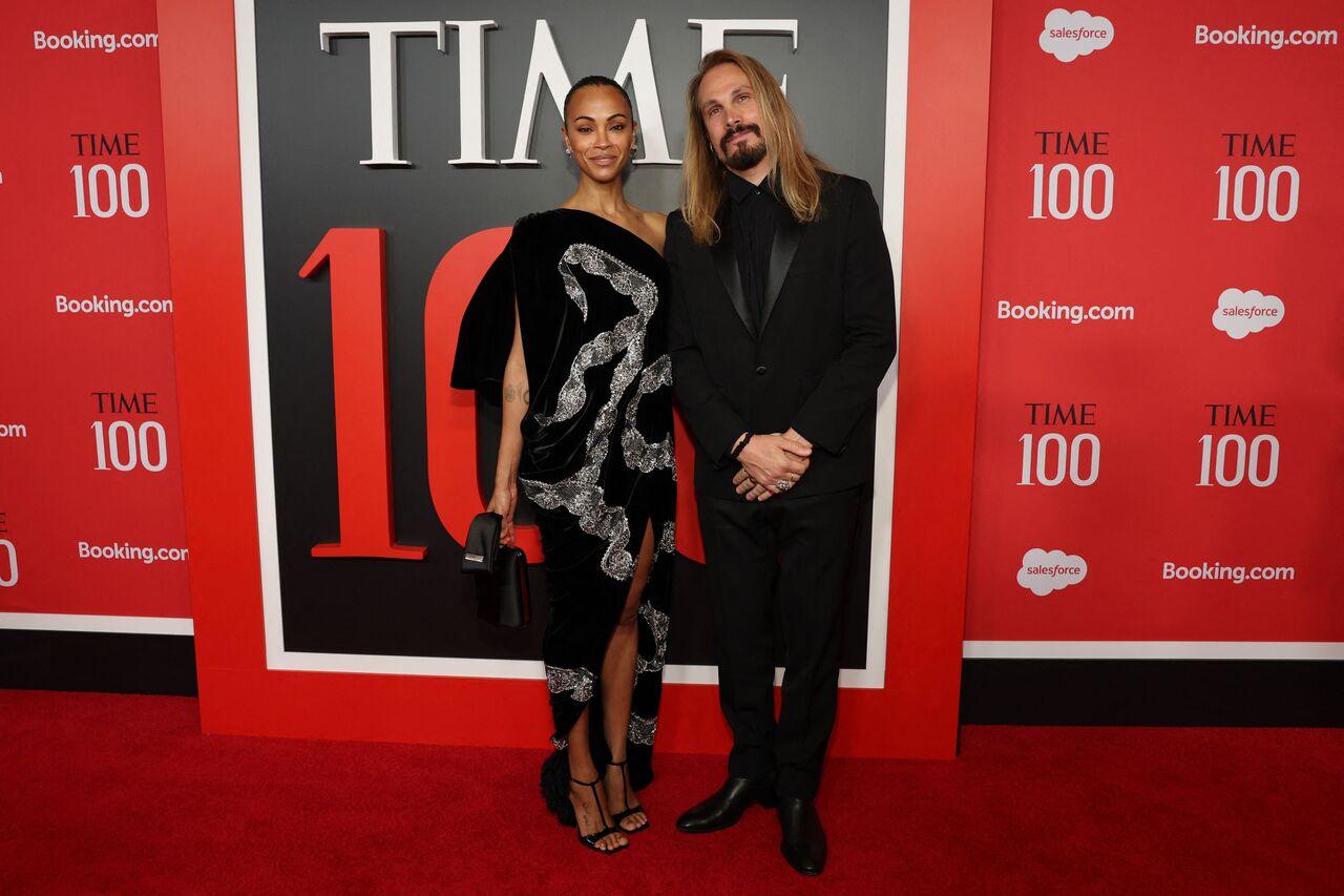 Zoe Saldana looks stunning in a black velvet, one-shoulder Schiaparelli gown featuring an artistic silver serpent design that winds down the body. She keeps the styling sleek and sophisticated with a high-bun hairstyle.