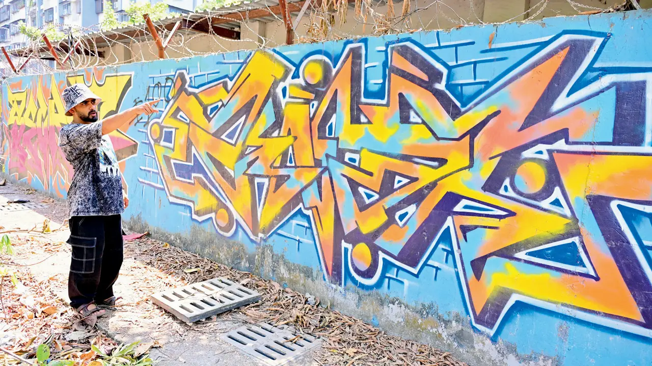 Omkar Dhareshwar with graffiti on the Wall of Fame, a kilometre-long stretch of walls with uninterrupted artworks. PICS/SHADAB KHAN