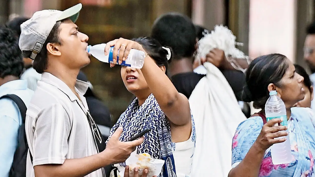 A man with hands occupied by a snack packet and his mobile phone gets help to quench his thirst at CSMT. PIC/ASHISH RAJE
