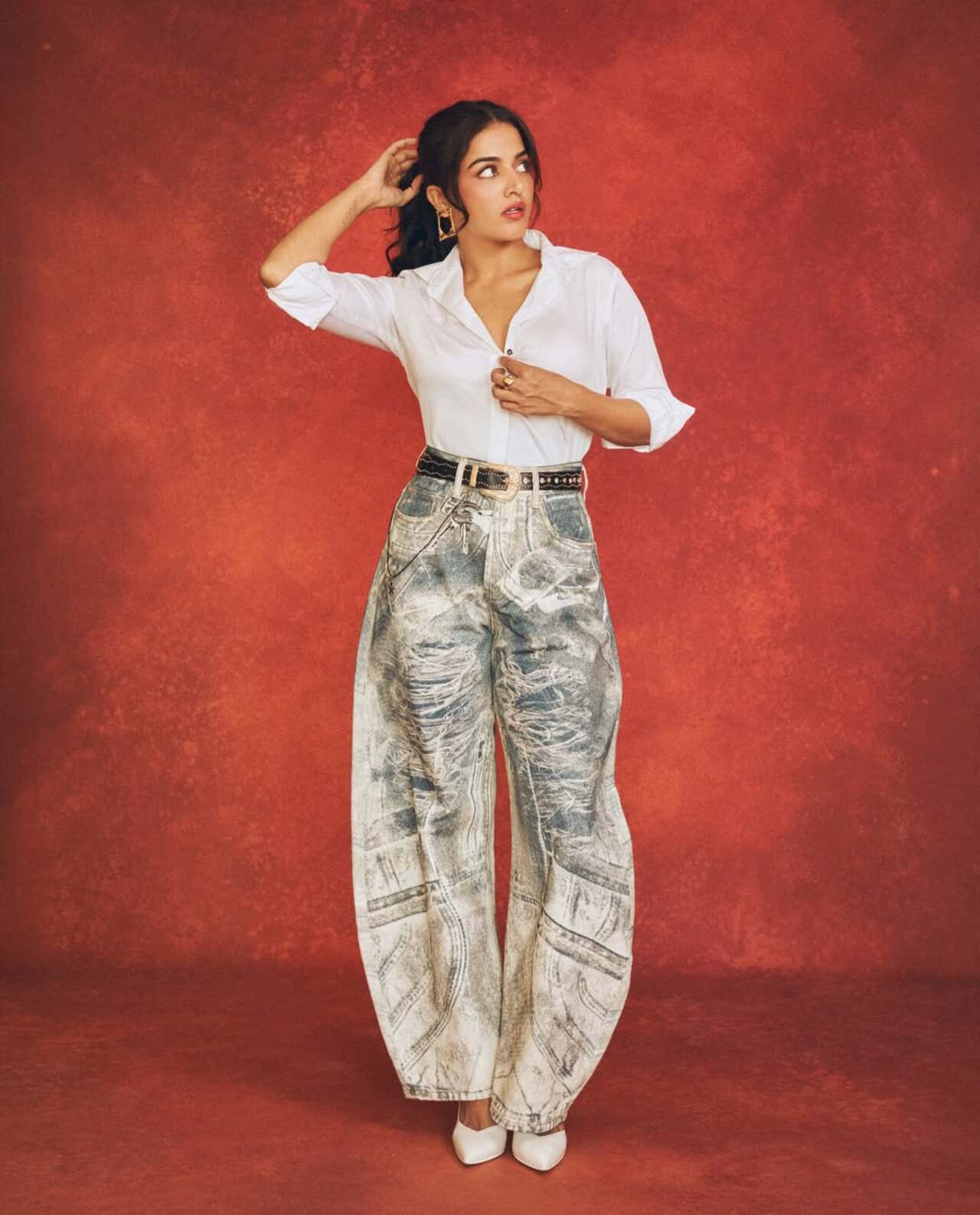 Wamiqa Gabbi sports a chic, modern look by pairing a classic white button-down shirt with oversized, high-waisted trousers featuring a unique distressed denim print.&nbsp;