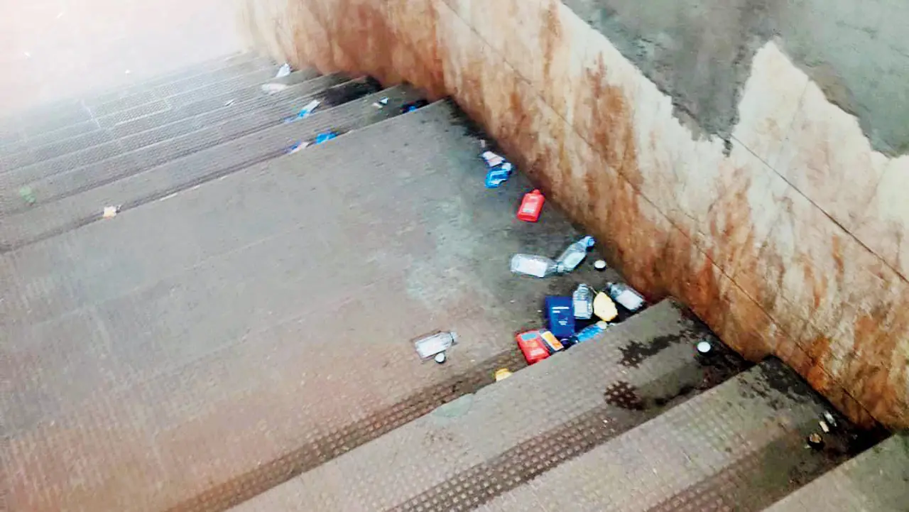 Empty alcohol bottles discarded in the subway with paan-stained walls