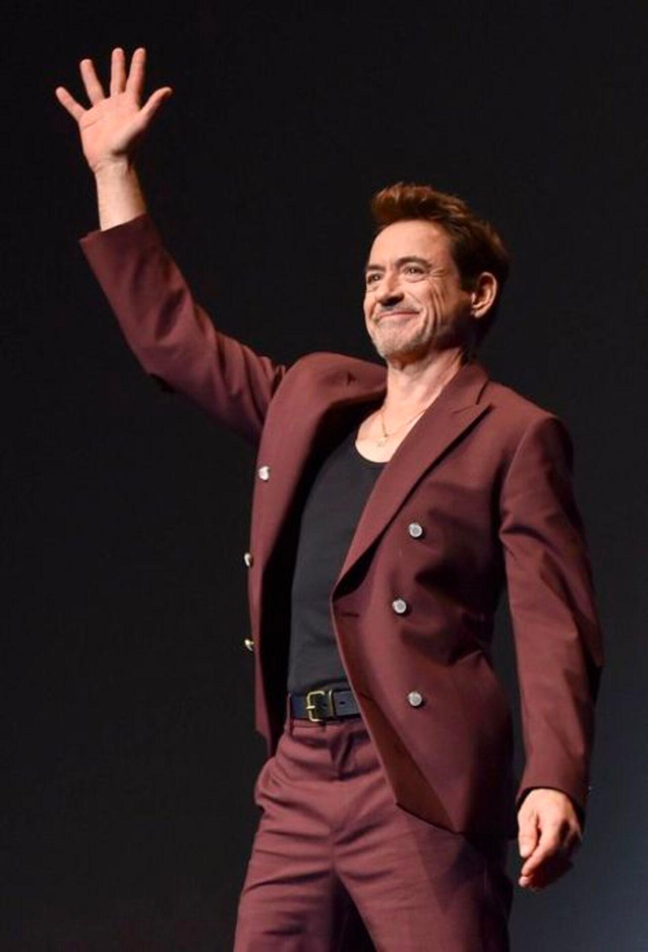 Robert Downey Jr wears a stylish and bold burgundy double-breasted suit, paired with a black t-shirt for casual and effortless charm.