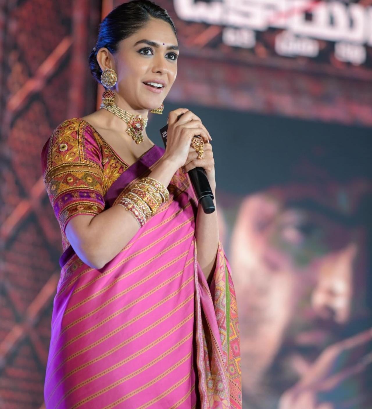 Mrunal Thakur dazzled at the Dacoit pre-release event in a pink saree featuring yellow line detailing along the border. She paired the vibrant drape with statement gold jewellery&mdash;stacked bangles, a choker necklace, and matching earrings.