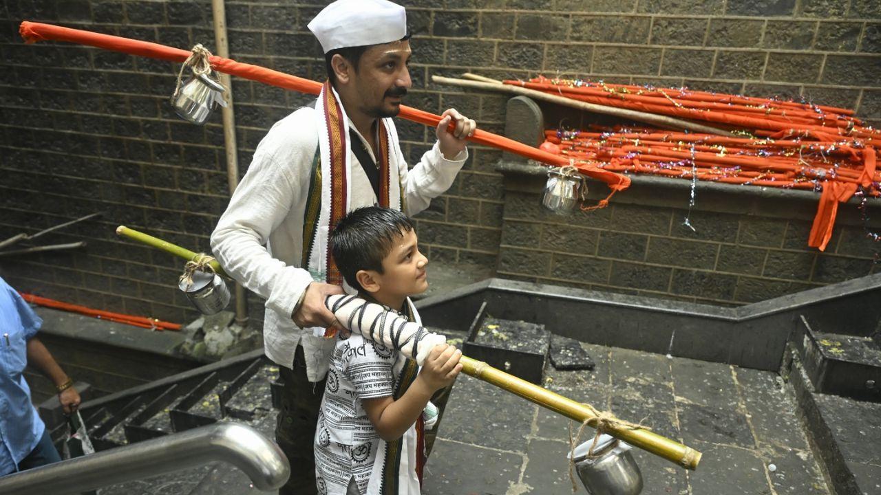 A devotee and his young son carry kanwars with sacred water as they climb the steps of Shree Babulnath Mandir during the traditional Kanwar Yatra A devotee and his young son carry kanwars with sacred water as they climb the steps of Shree Babulnath Mandir during the traditional Kanwar Yatra 