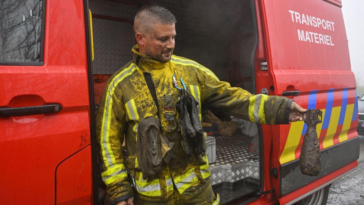 A firefighter holds a shell he found from World War II as he takes part operations