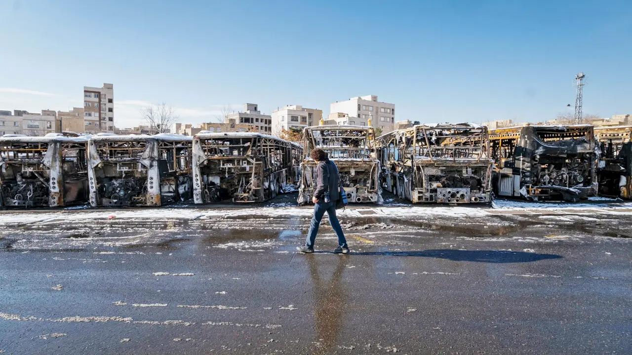 A man walks past buses that were set ablaze during anti-government protests in Tehran. PIC/Getty Images