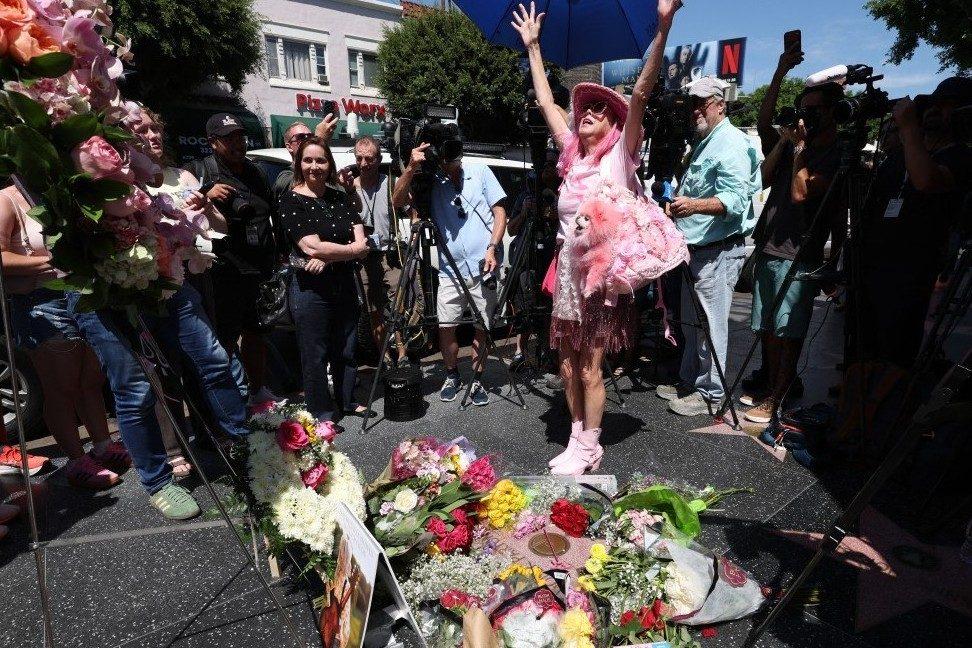 A woman reacts emotionally in front of flowers and a wreath placed at Dolly Parton’s Hollywood Walk of Fame star in Los Angeles.