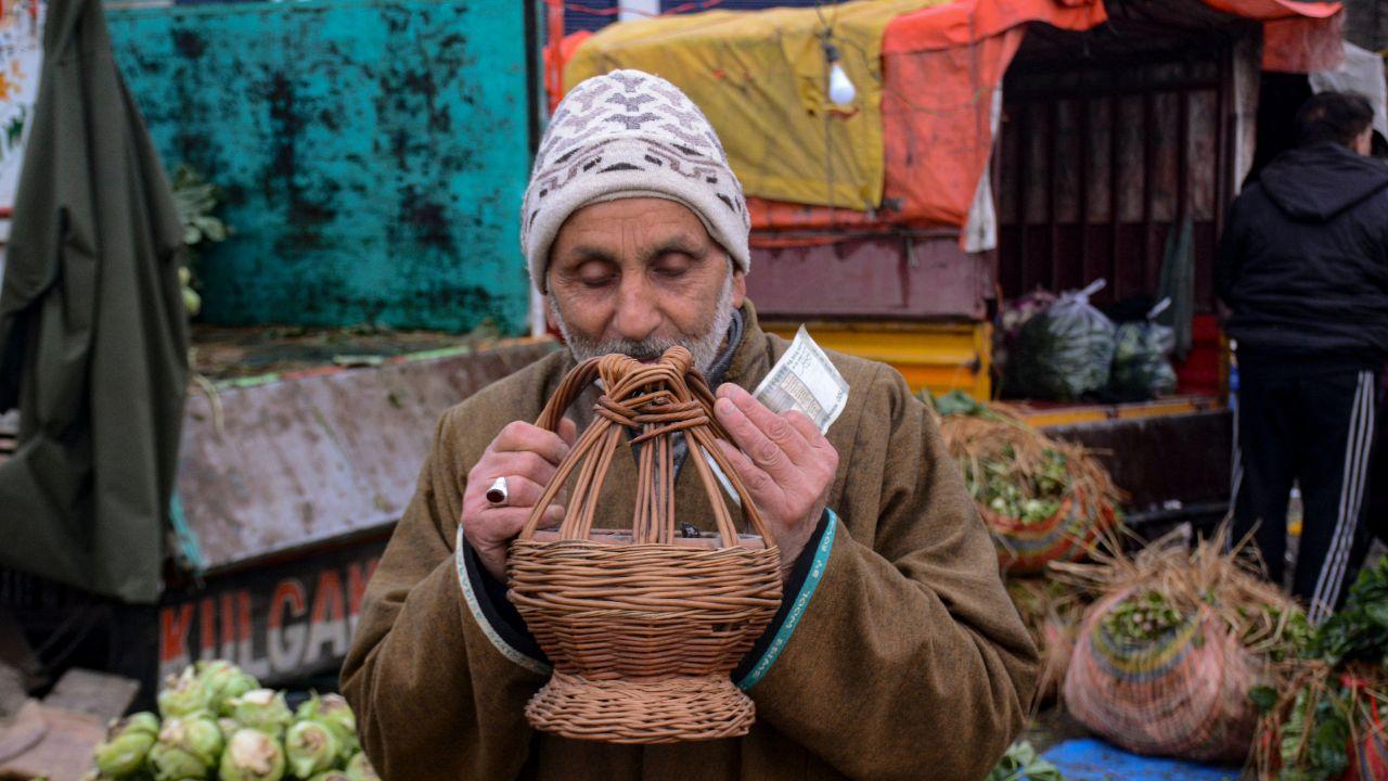 An elderly man warms himself using 'Kangri', a traditional fire pot, during a cold winter morning, at a wholesale vegetable mandi in Jammu Kashmir's Srinagar