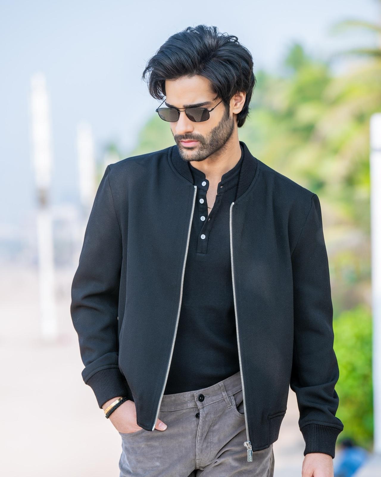 Aaman Devgan rocks a black jacket layered over a black T-shirt, paired with grey pants. It is a modern look that balances casual cool with effortless style.