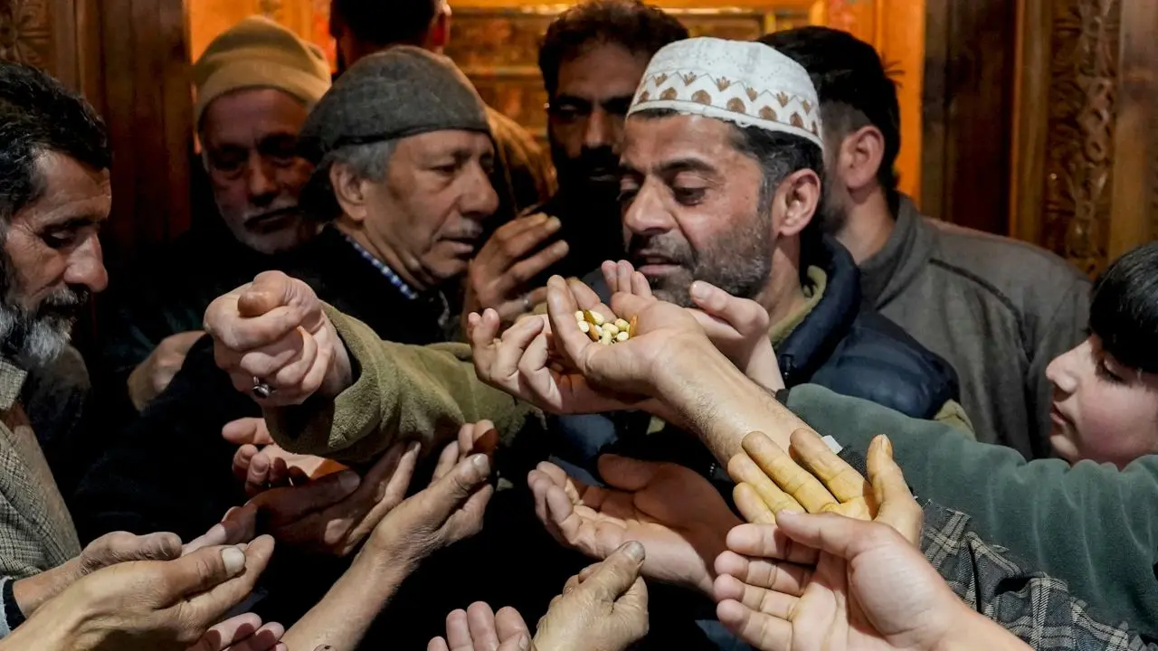 A man distributes dry fruits to people after prayers during the holy month of 'Ramzan' at a mosque, in Srinagar, Jammu and Kashmir
