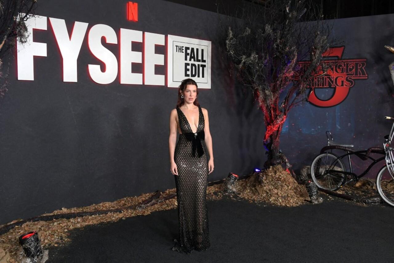 Millie Bobby Brown turned heads in a figure-hugging mesh gown with a plunging neckline, featuring a striking bodice cutout highlighted by a large black bow with a jeweled center. 