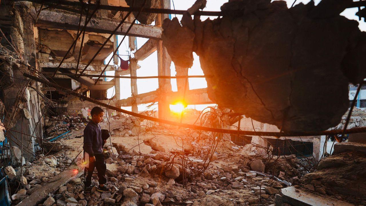 Amid the ruins of Bureij refugee camp, a young displaced Palestinian boy makes his way across debris ahead of the Ramadan iftar meal