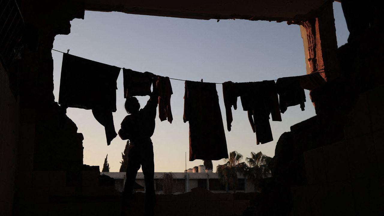 A displaced Palestinian woman hangs laundry in the open air before preparing for iftar during Ramadan, surrounded by the ruins of the camp, located in central Gaza