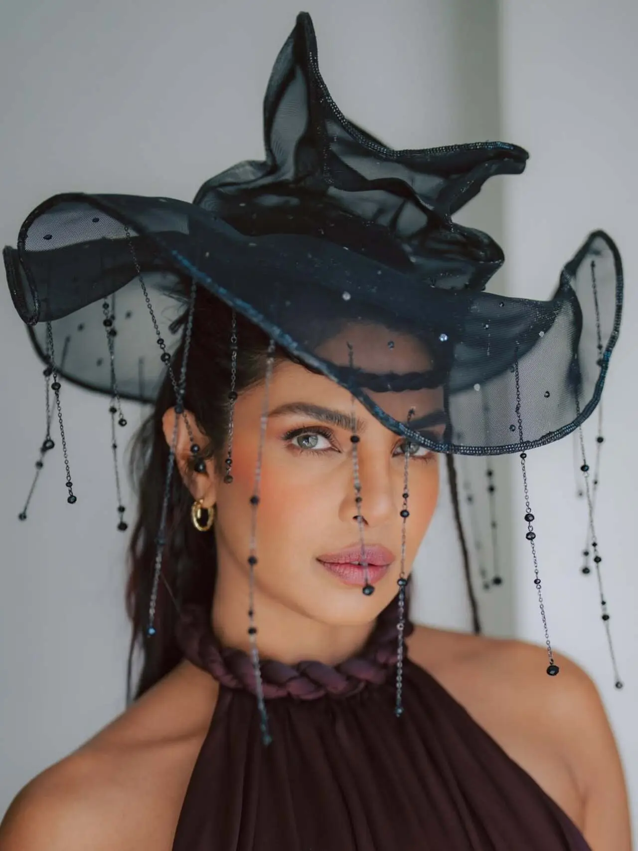 Priyanka Chopra looks absolutely striking in this close-up shot. The dramatic black sheer hat, detailed with delicate bead strands, creates a bold and artistic fashion statement.