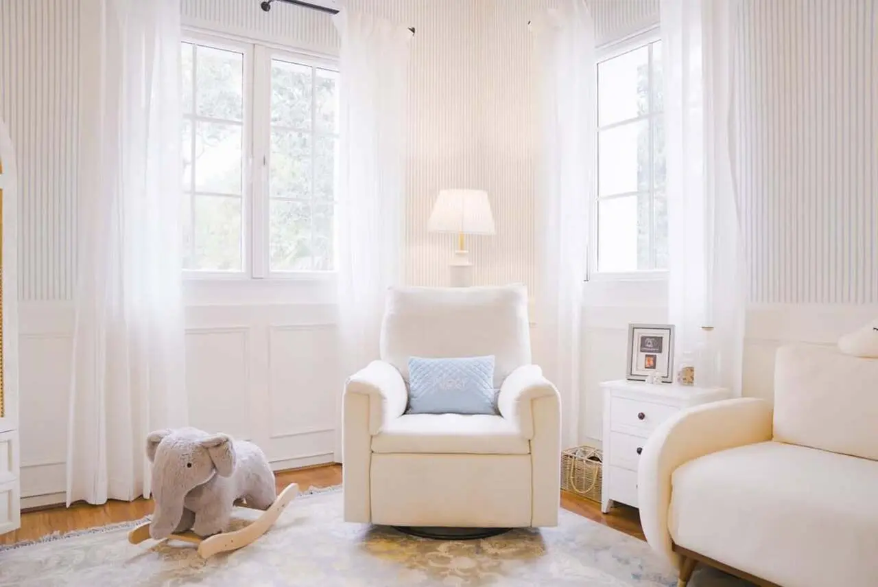 We can also see a large French windows with transparent white curtains flowing in. You can see a cushioned armchair in a corner and a sofa.