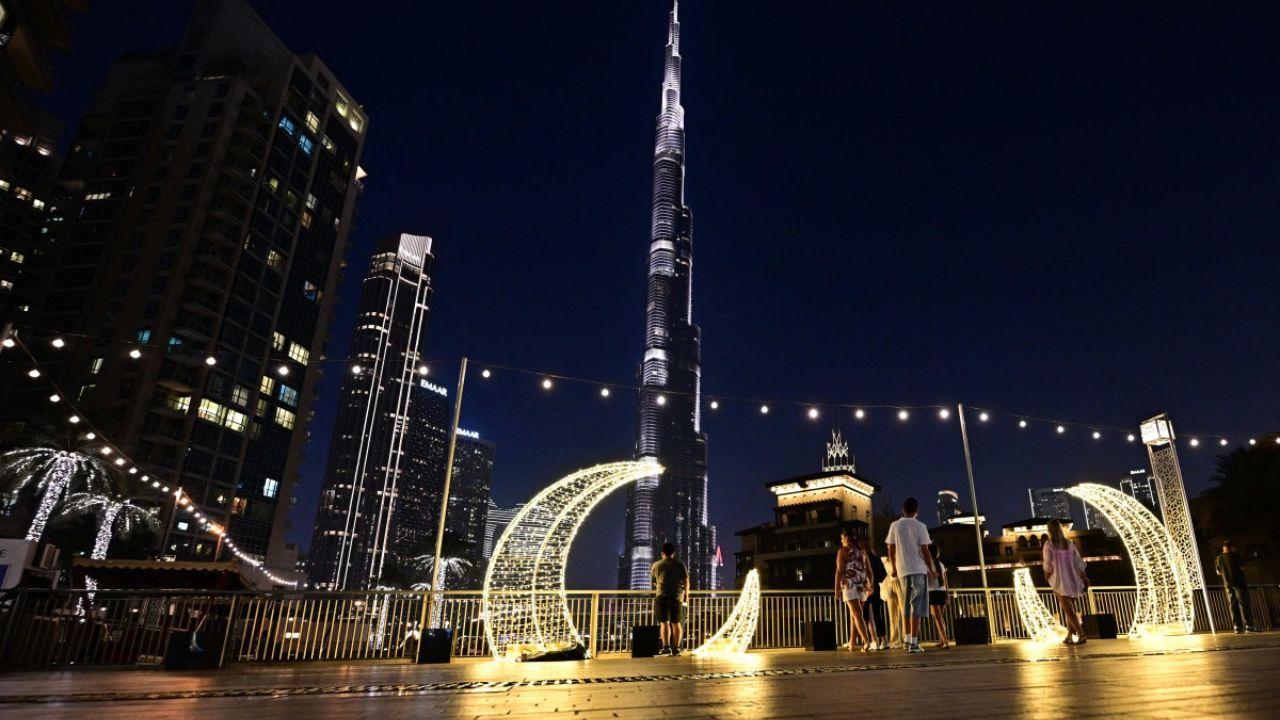 People stand near crescent-shaped festive decorations near the Burj Khalifa in central Dubai on Tuesday