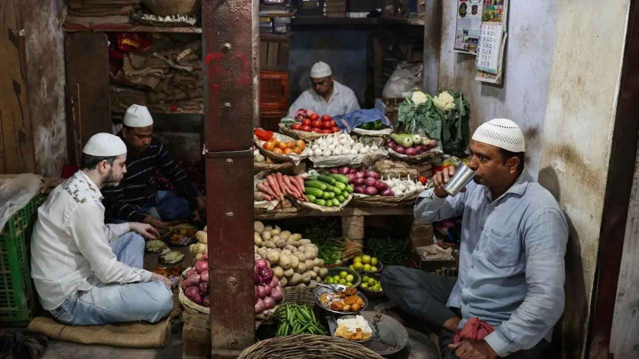 Muslim vegetable vendors gather inside a shop to break their fast at sunset in Varanasi, marking a brief moment of prayer and reflection amid their daily work routine