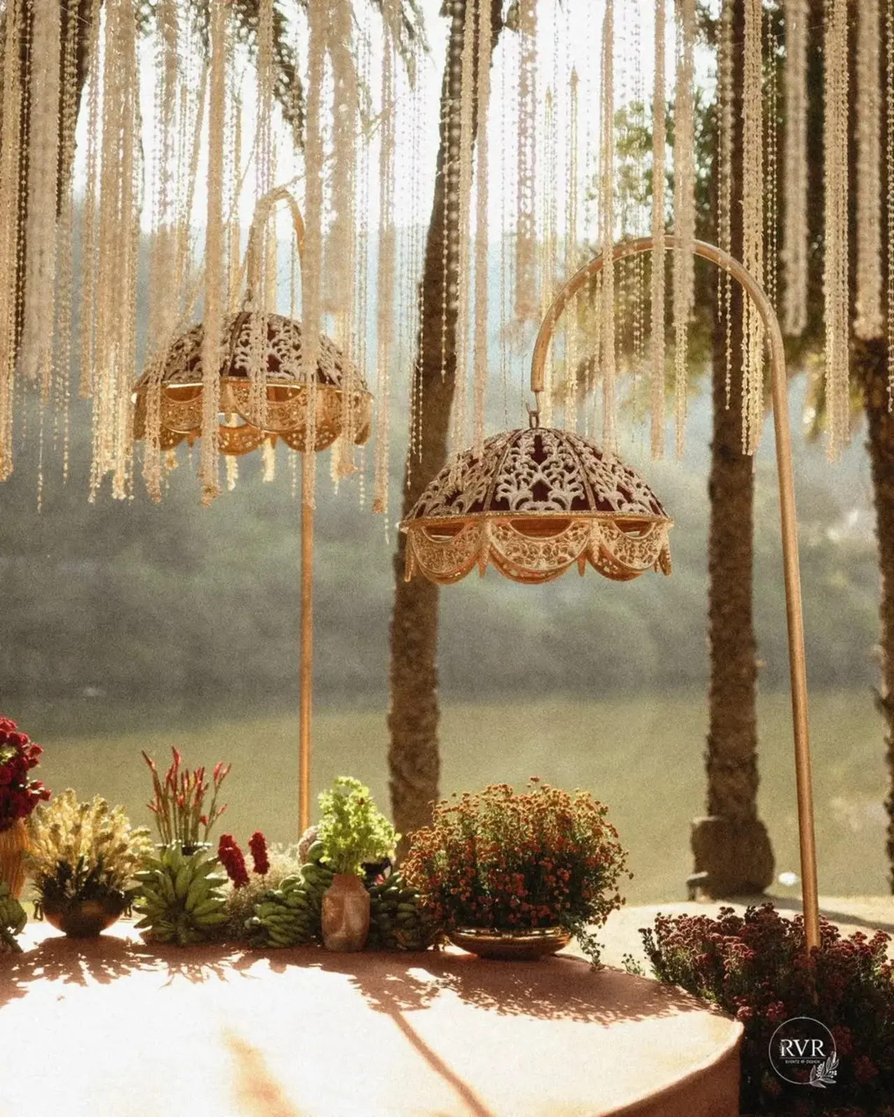 Large red parasols with gold detailing add a royal touch, while terracotta pillars adorned with delicate white floral garlands frame the space beautifully