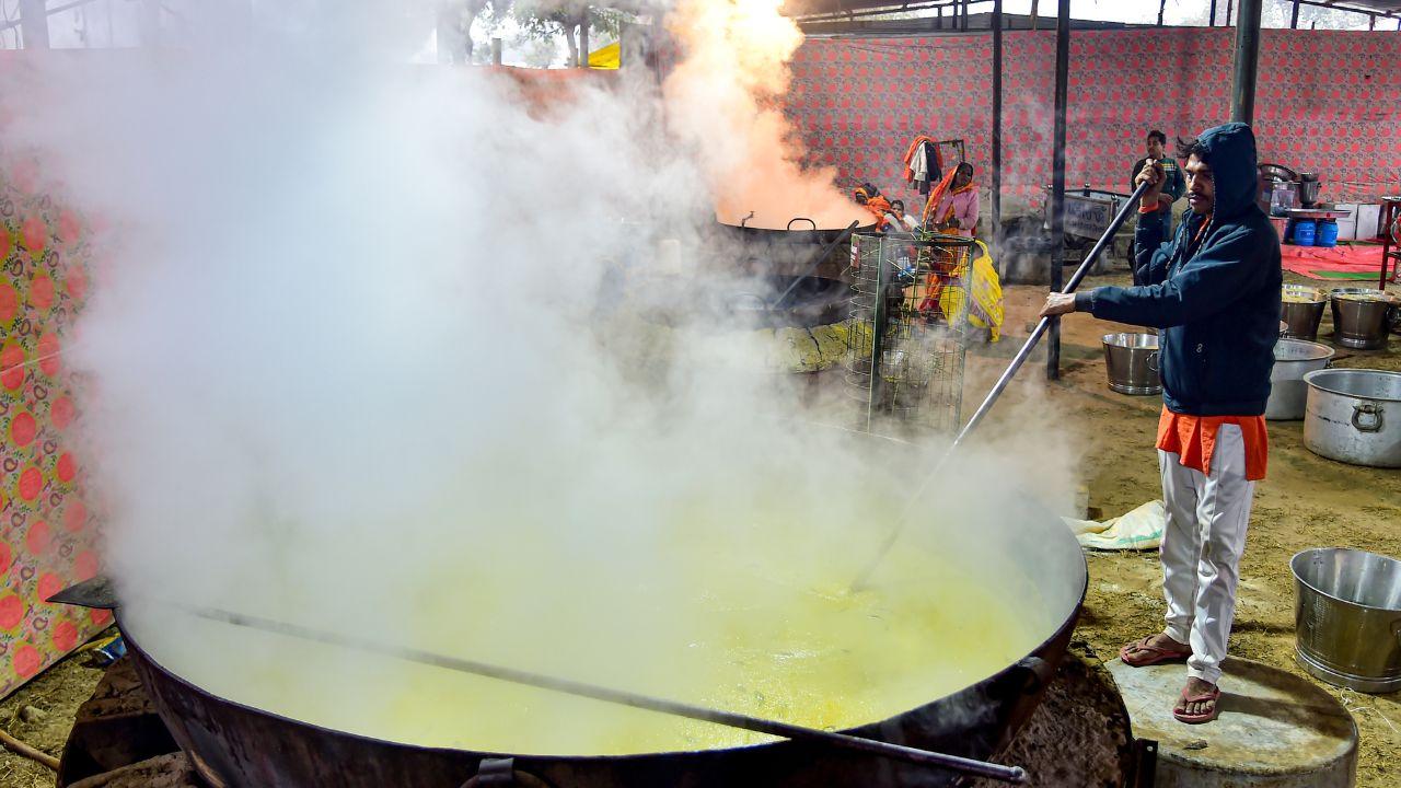Through the chill of dawn, with fires lit against the winter cold, volunteers prepare free meals for scores of pilgrims gathered at the Sangam